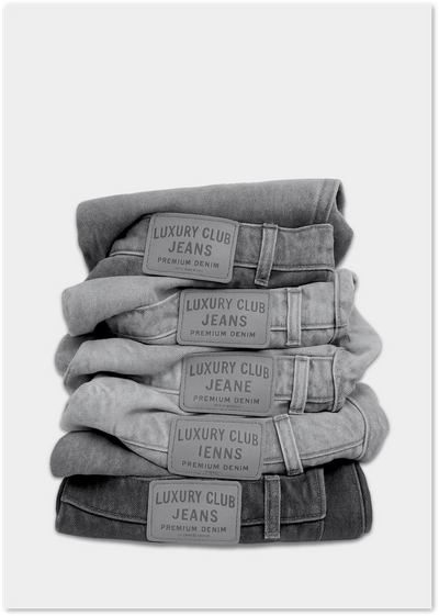 Stack of folded grey denim jeans with Luxury Club Jeans leather patches, photographed on white background