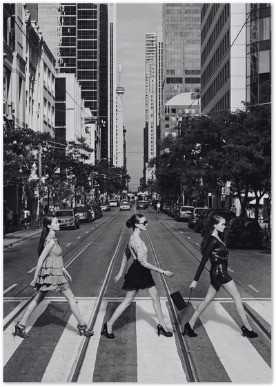 Black and white photo of three fashion models crossing a Toronto street with CN Tower behind