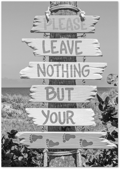 Black-and-white photo of a wooden beach sign reading Please Leave Nothing But Your Footprints