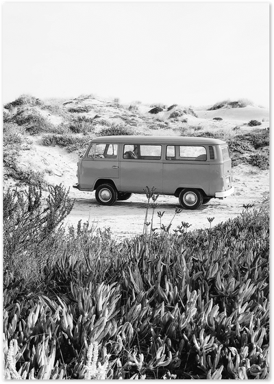 Black and white photo of a vintage camper van parked among beach dunes and coastal grasses